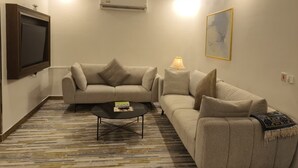 Una sala de estar con un sofá, una mesa de centro, un televisor y una lámpara.