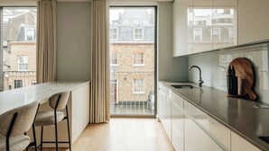 Eine moderne Küche mit einem großen Fenster, einem Barhocker und einem Holztisch zum Schneiden auf der Arbeitsplatte.
