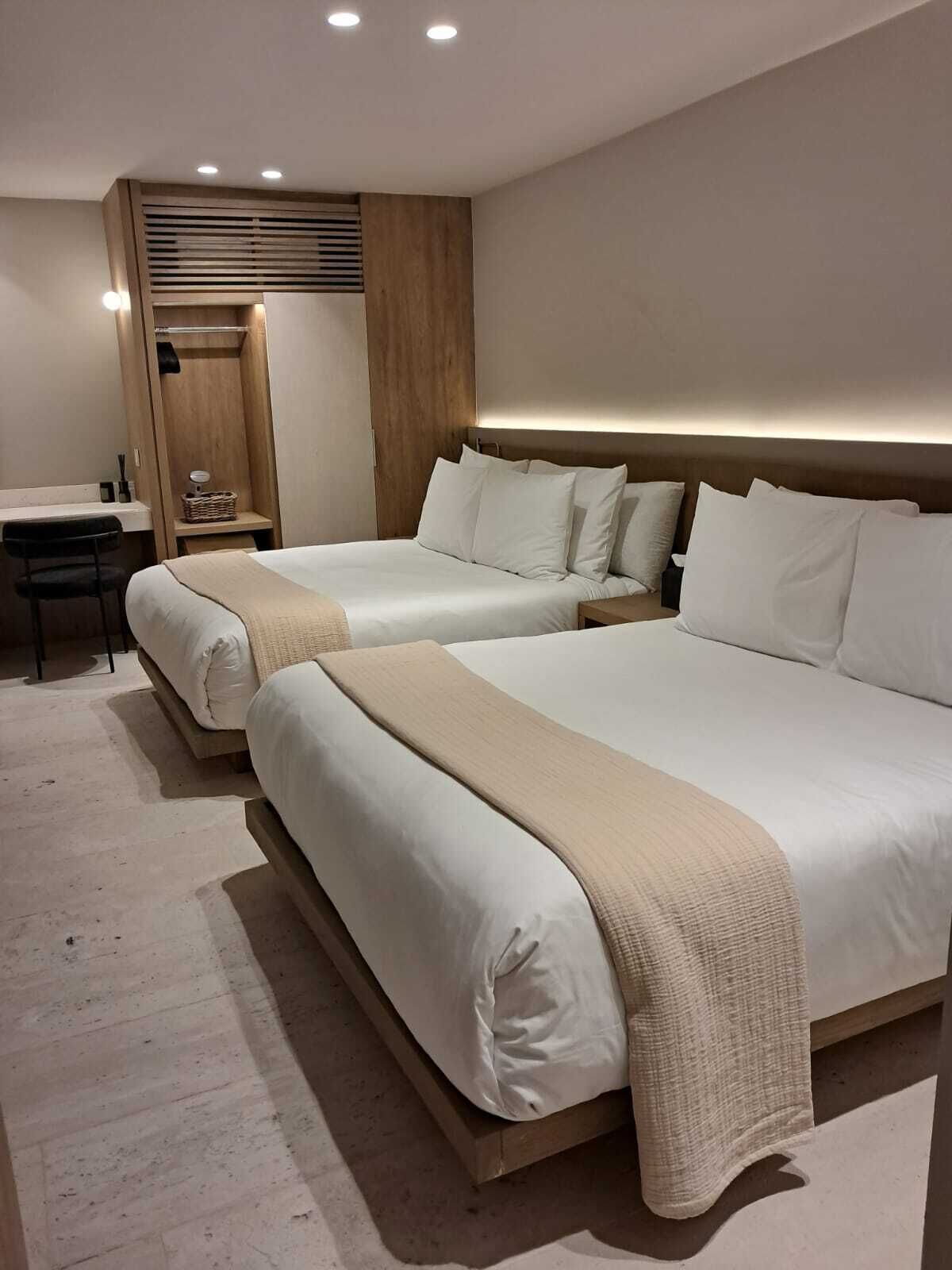 A hotel room with two beds, a desk, and a wardrobe.