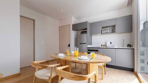 Une cuisine moderne dotée d’appareils électroménagers intégrés, un coin repas avec des chaises en bois et une grande fenêtre.