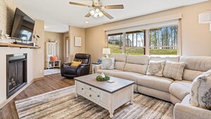 A living room with a fireplace, a ceiling fan, a sofa, a recliner, and a television. - The Hideaway: Large (7BD), Modern, Lakeview, Slip (LaFollette)