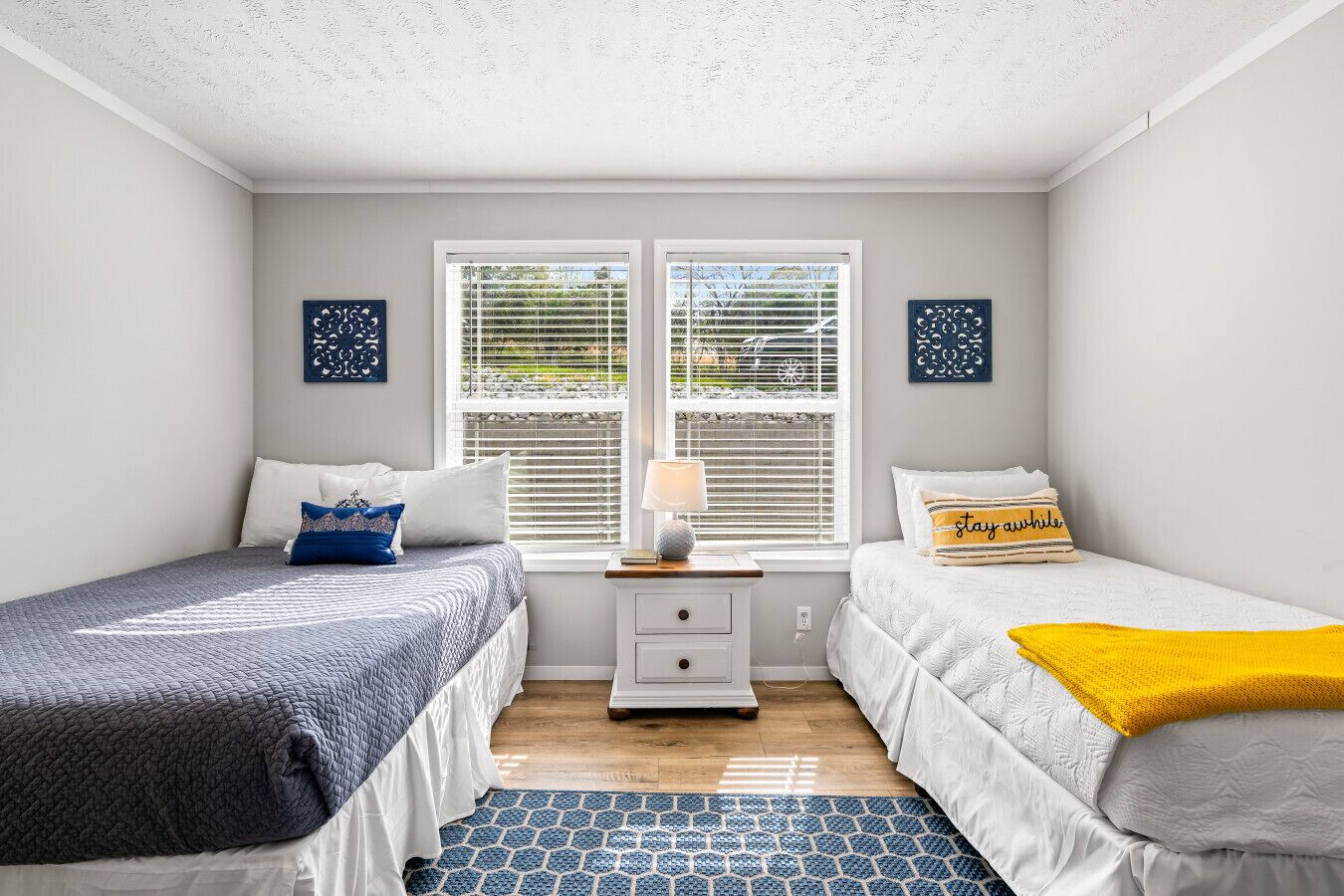 A bedroom with two beds, a nightstand, a lamp, and two wall art pieces.