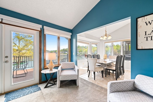 A spacious room with a balcony, a dining area, and a view of the outdoors.