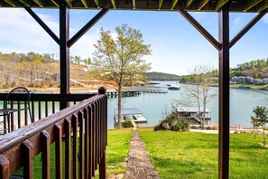 Un pontile in legno con vista su un lago tranquillo, imbarcazioni ormeggiate e una zona erbosa.