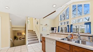 A kitchen with a dishwasher, a sink, and a window overlooking a tree. - Livin` the Dream: Lakefront, Dock, Firepit, 16 (LaFollette)