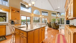 A spacious kitchen with wooden cabinets, a large island, and a view of the outdoors. - Poolside Paradise: Lakefront; Private Pool; Dock (LaFollette)
