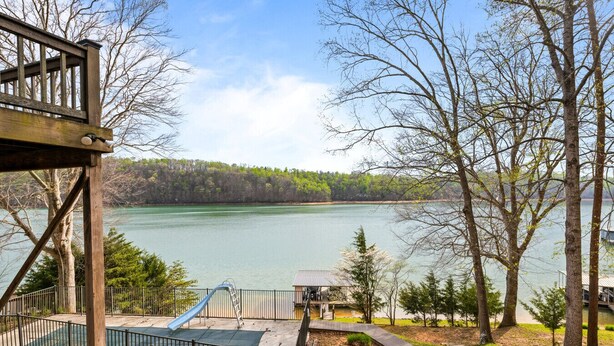 A lakeside deck with a playground, a small building, and a view of the lake and forest. - Poolside Paradise: Lakefront; Private Pool; Dock (LaFollette)