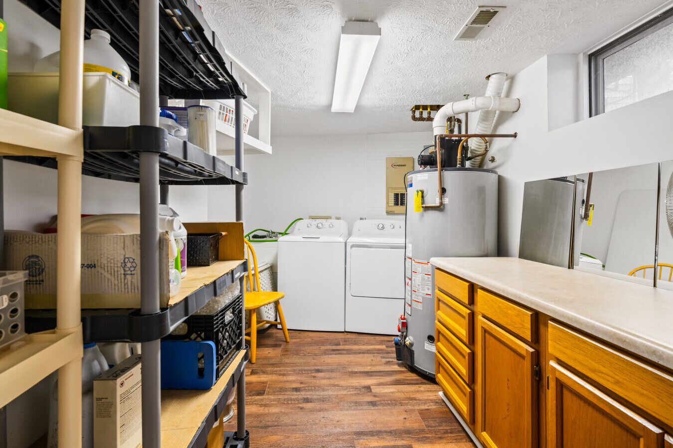 A laundry room with a washing machine, dryer, and stacked shelves with cleaning supplies.