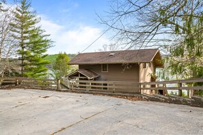 A cabin with a wooden deck, a small porch, and a view of a lake. - Poolside Paradise: Lakefront; Private Pool; Dock (LaFollette)