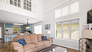 A spacious living room with a sofa, coffee table, and a view of the kitchen and balcony.