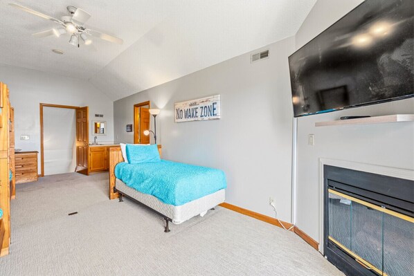 A bedroom with a bed, a dresser, a vanity, a ceiling fan, a fireplace, and a sign that reads 'NO WAKE ZONE'. - Bunkers & Boats: Ridge/Lake/Golf Views; Slip; 10 (LaFollette)