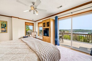 A bedroom with a large bed, a ceiling fan, a TV, and a balcony with a view of a lake. - Bunkers & Boats: Ridge/Lake/Golf Views; Slip; 10 (LaFollette)
