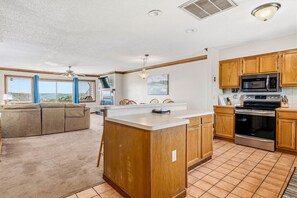 Una cocina amplia con armarios de madera, una isla central y un comedor con sofá y sillas.