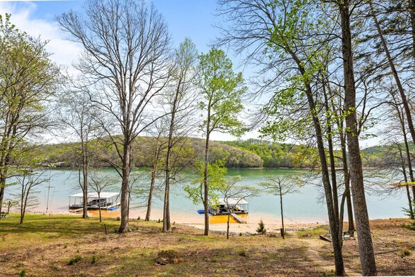 A lakeside view with trees, a dock, and a small boat.