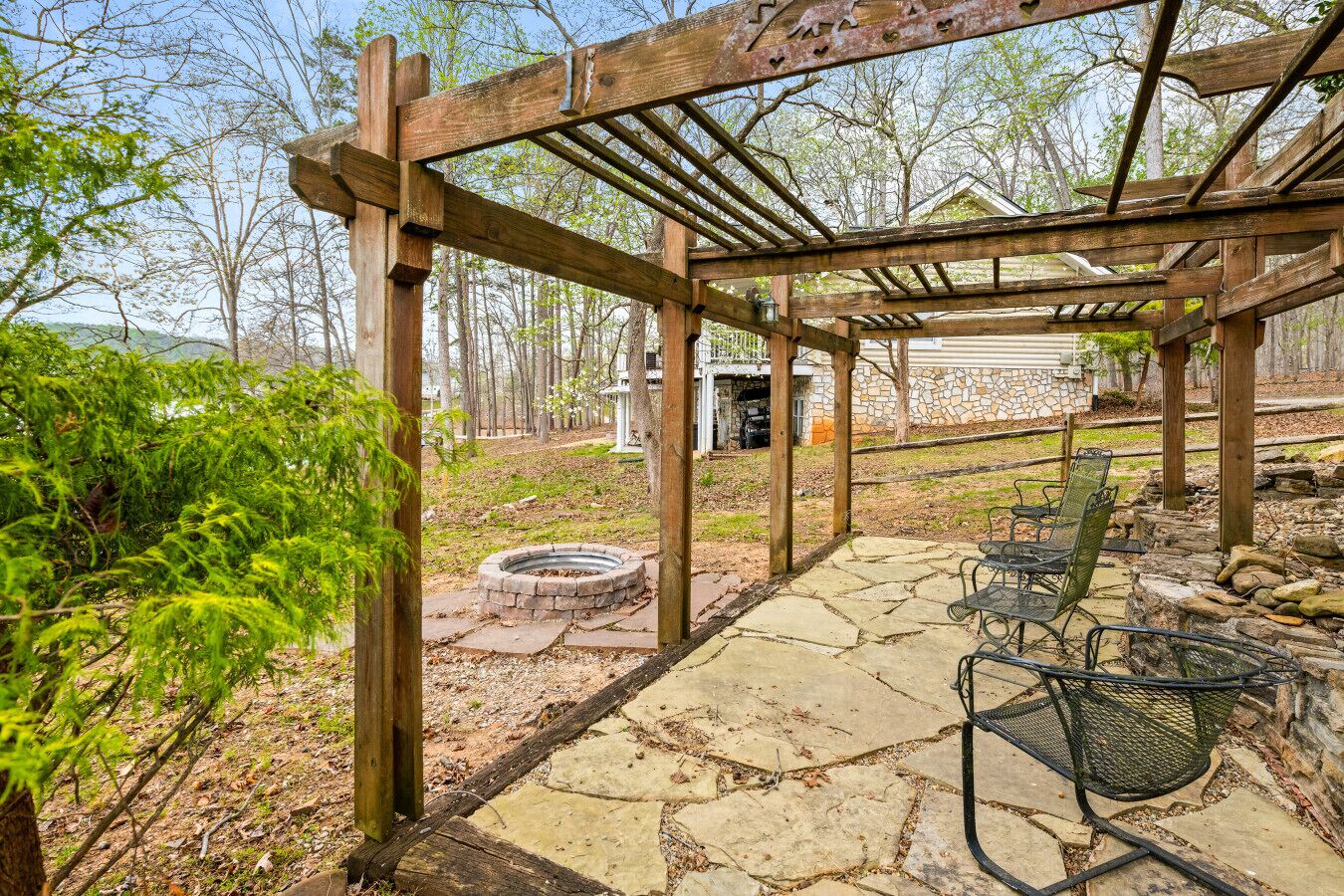 Una pérgola de madera con un patio de piedra, mobiliario exterior y una chimenea.