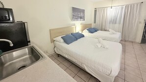 Une chambre d’hôtel avec deux lits, une kitchenette et une vue sur la ville.