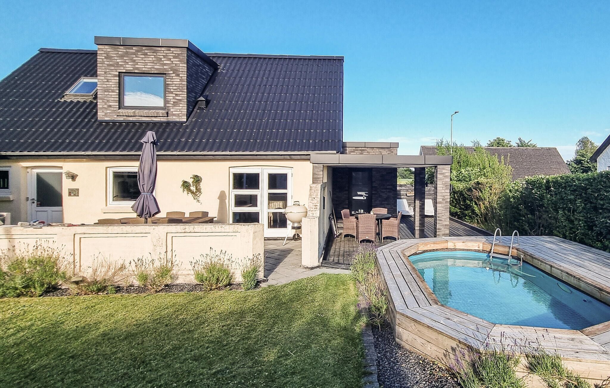 A modern house with a swimming pool, a covered patio, and a well-maintained lawn.