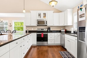 Una cocina moderna con armarios blancos, electrodomésticos de acero inoxidable y piso de madera.