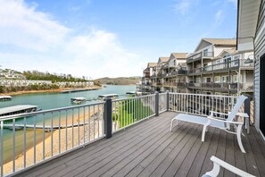 Un balcon avec vue sur une rivière, des bateaux et une côte lointaine.