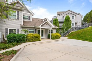A suburban residential area with detached houses, a driveway, and a grassy hill. - 112#4 Condo: Modern, Lakefront, Spacious (LaFollette)