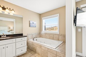 A bathroom with a bathtub, a vanity with a mirror, and a window with a view. - 112#4 Condo: Modern, Lakefront, Spacious (LaFollette)
