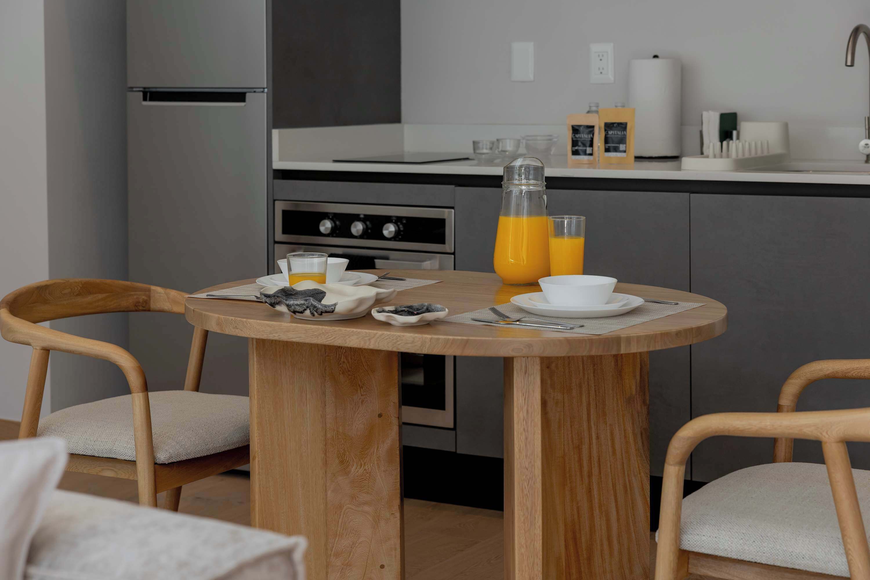 Une cuisine de taille réduite comprenant une table à manger, des chaises et un réfrigérateur.