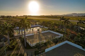 A large open area with a pool, surrounded by palm trees and a view of a runway. - Hermoso departamento en Dream Diamante Acapulco (Barra Vieja)