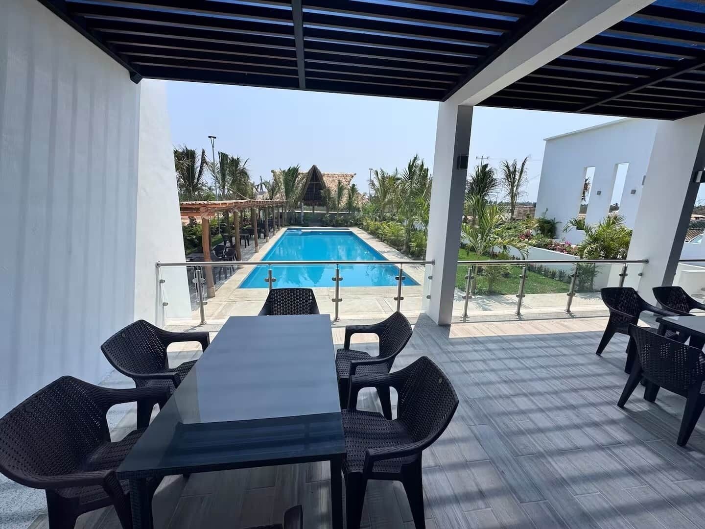 Ein überdachter Außenbereich mit Pool, Tischen und Stühlen.