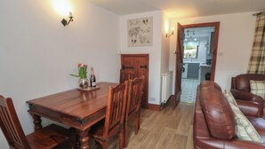 A dining area with a wooden table and chairs, a sofa, and a kitchen in the background.