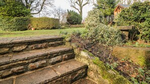 Stone steps leading up to a garden area with a stone wall and greenery.