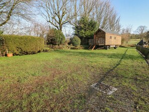 A wooden cabin with a porch, surrounded by a grassy yard and trees. - Wayside Cottage at Wayside Farm (Matlock)