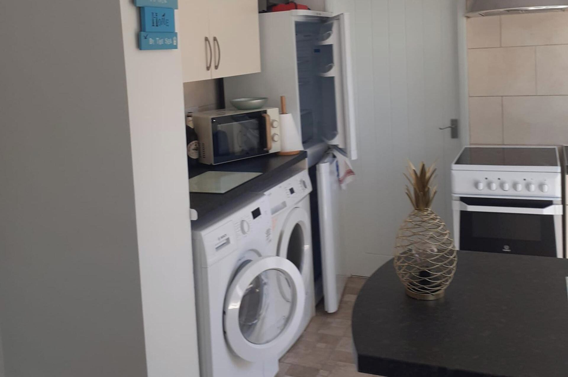 A compact kitchen with a washing machine, microwave, and oven.