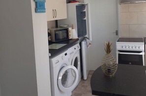 Una cocina funcional con lavadora, microondas y horno.