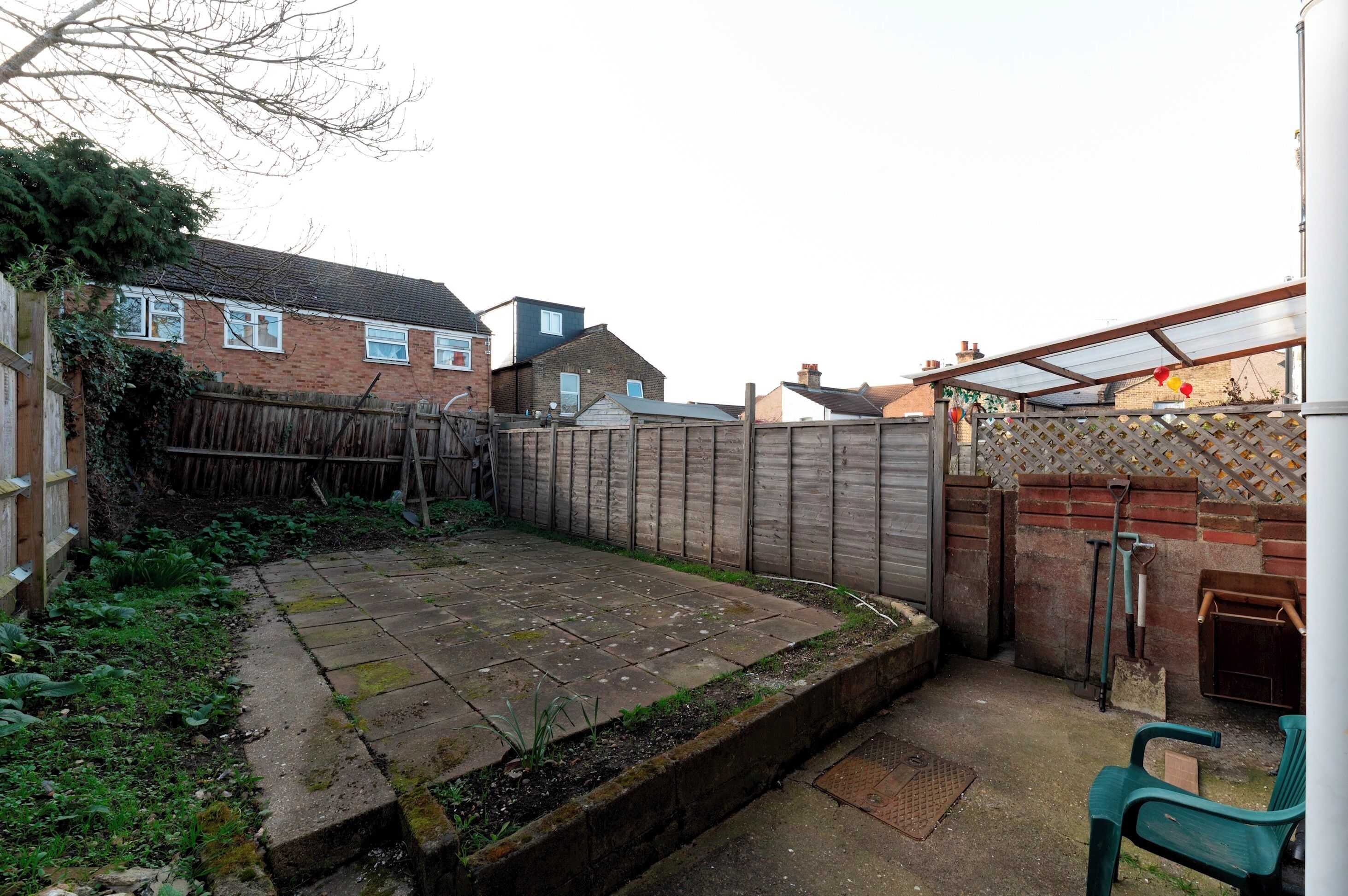 A backyard with a paved area, a wooden fence, and a brick wall.