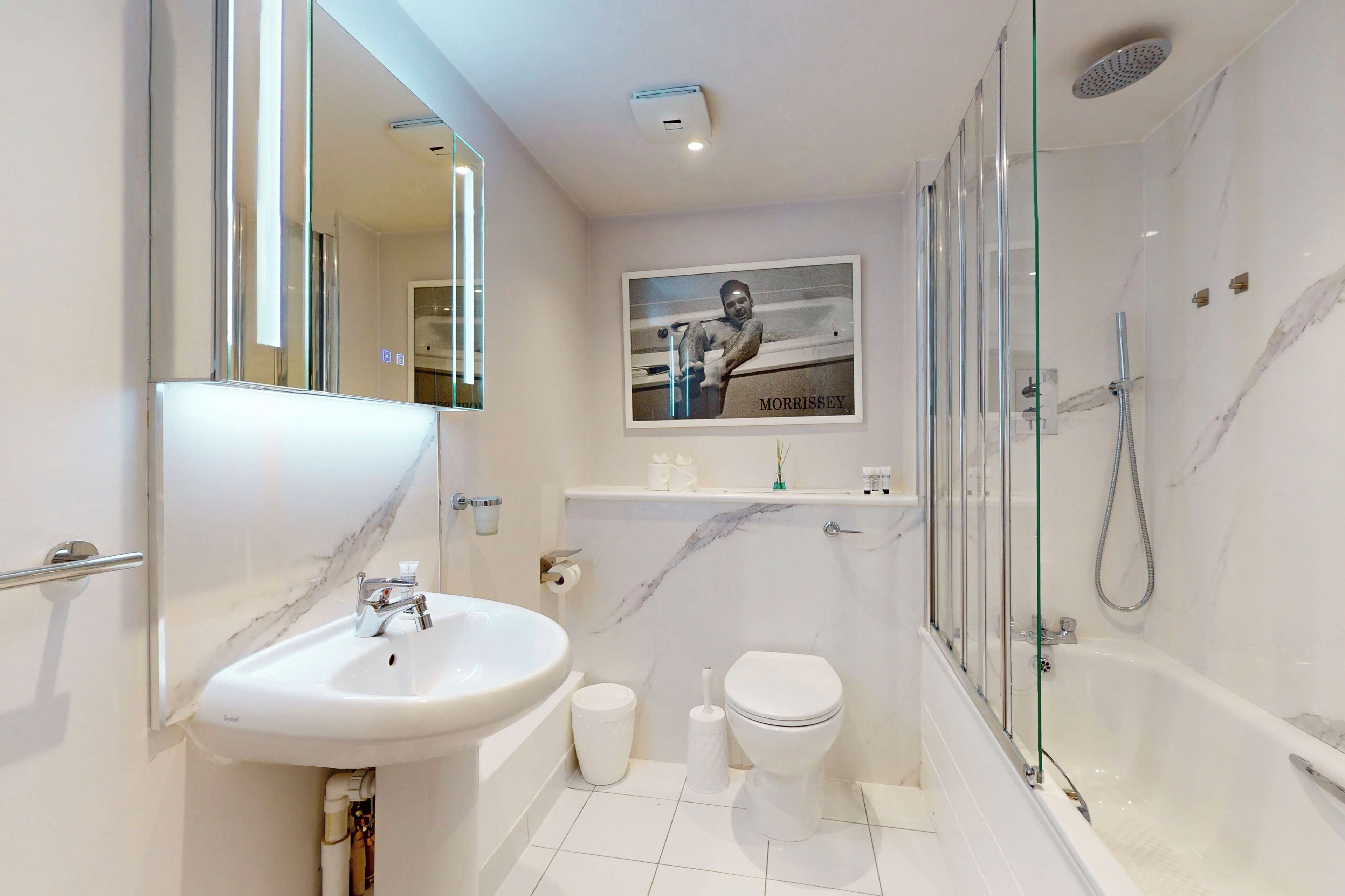 Une salle de bain moderne avec un lavabo en marbre, des toilettes et une douche à parois de verre.