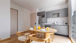 Een moderne keuken met inbouwapparatuur, een eethoek met houten stoelen en een groot raam.