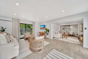 A modern living room with a white sofa, a round wooden coffee table, and a dining area with a white table and chairs. - Waterfront Retreat Studio #4🌴 20-Min Walk to the Beach Summer Deals! (Fort Lauderdale)