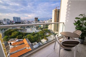 A balcony with a table and chairs, overlooking a cityscape with buildings and trees. - Apartamento Amueblado en Naco – Piso 12 (Santo Domingo)