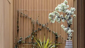 A seating area with two chairs and a table, a potted plant, and a vase with flowers against a wooden wall. - Luxury Garden Suit in Recoletos (Madrid)