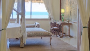 Une chambre avec un lit, un bureau et une vue sur l’océan.
