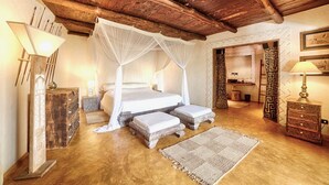 Une chambre à coucher avec un plafond en bois, un lit à baldaquin, des tables de chevet et une petite table de nuit.