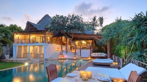 Un espace repas aménagé au bord de la piscine, avec une table pour deux, entouré de chaises longues et donnant sur la piscine.