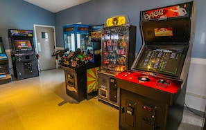 A row of arcade machines in a room with a plain wall and a door in the background.
