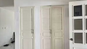 Een kamer met witte wanden, een witte deur met ruitpanelen en een witte vloer.