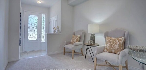 Un salon moderne avec deux fauteuils, une petite table ronde et une lampe.
