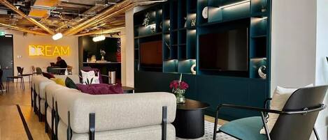 A modern lounge area with a sofa, chairs, and a wall-mounted display.
