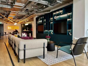Un espace de détente moderne comprenant un canapé, des fauteuils et un écran fixé au mur.