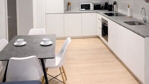 Une cuisine moderne avec des meubles blancs, une table à manger avec des chaises et un four à micro-ondes.