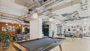 Une table de billard dans un espace intérieur moderne, avec des plafonds apparents et un éclairage de style industriel.