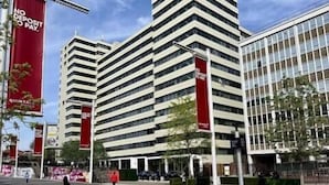 Un immeuble à plusieurs étages doté d’une architecture moderne, caractérisé par un angle bien marqué et une façade en verre.